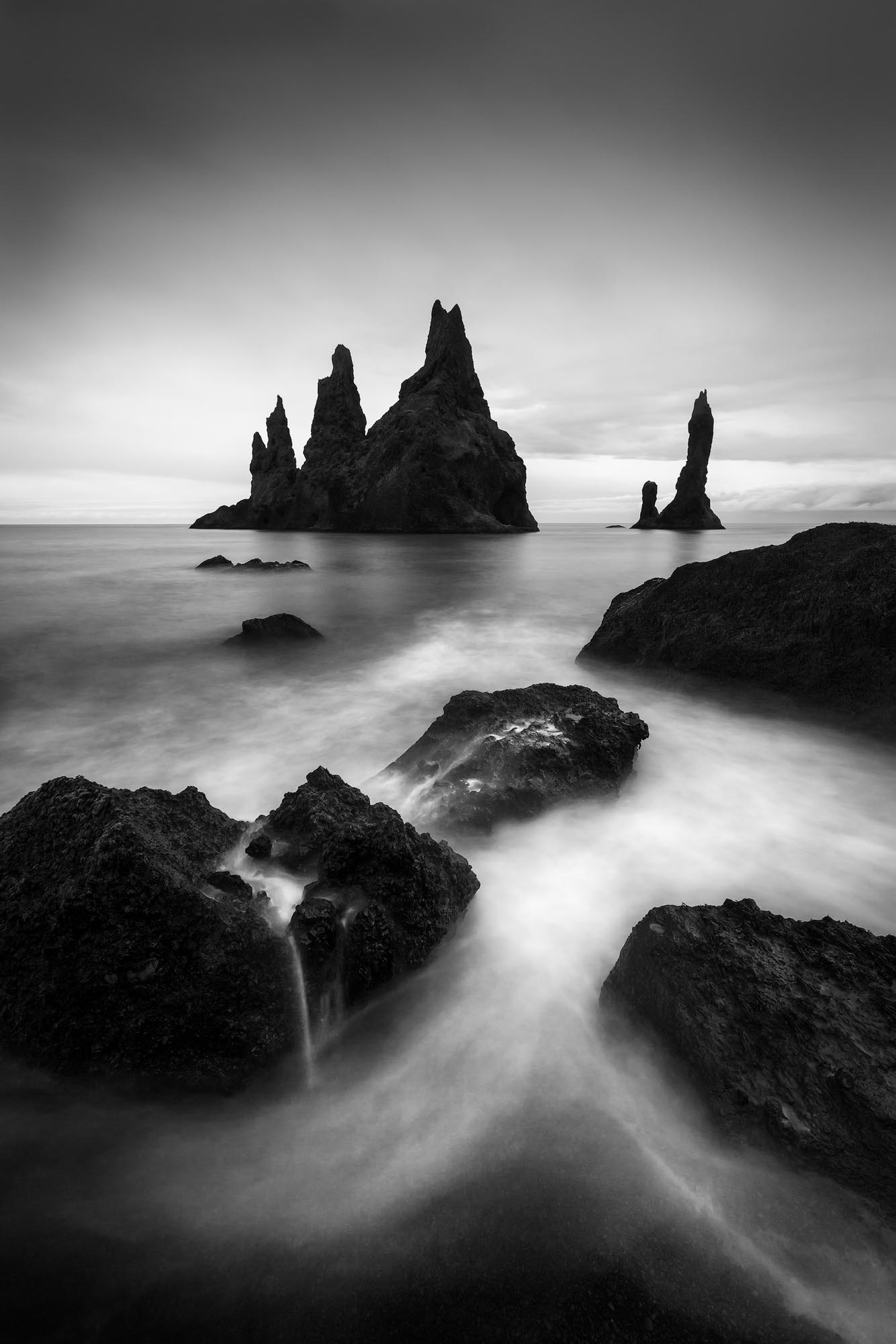 The iconic Reynisdrangar sea stacks loom over a small cove in Iceland. while the waves are usually intense in this area, on this...